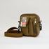 Small brown bag with a flap pocket, a pencil skinny pocket and a zipper on the right side with the adjustable strap showing. Left side facing image