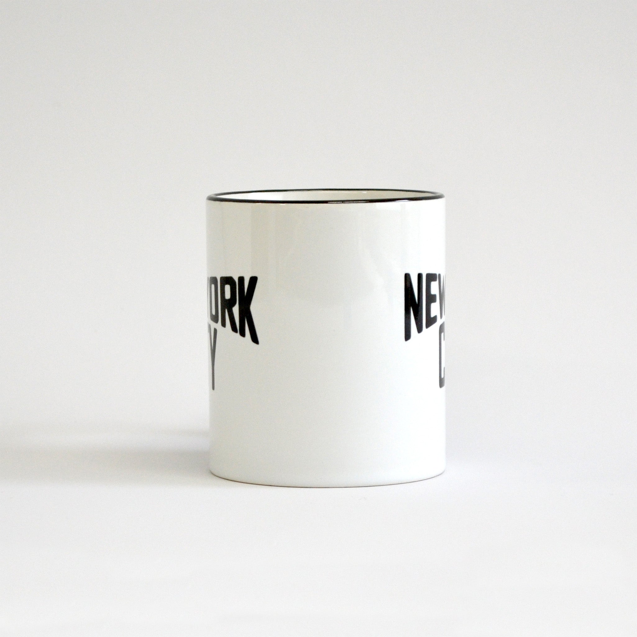 White coffee mug with black lettering of NEW YORK CITY - side view partially showing the words on the left and right