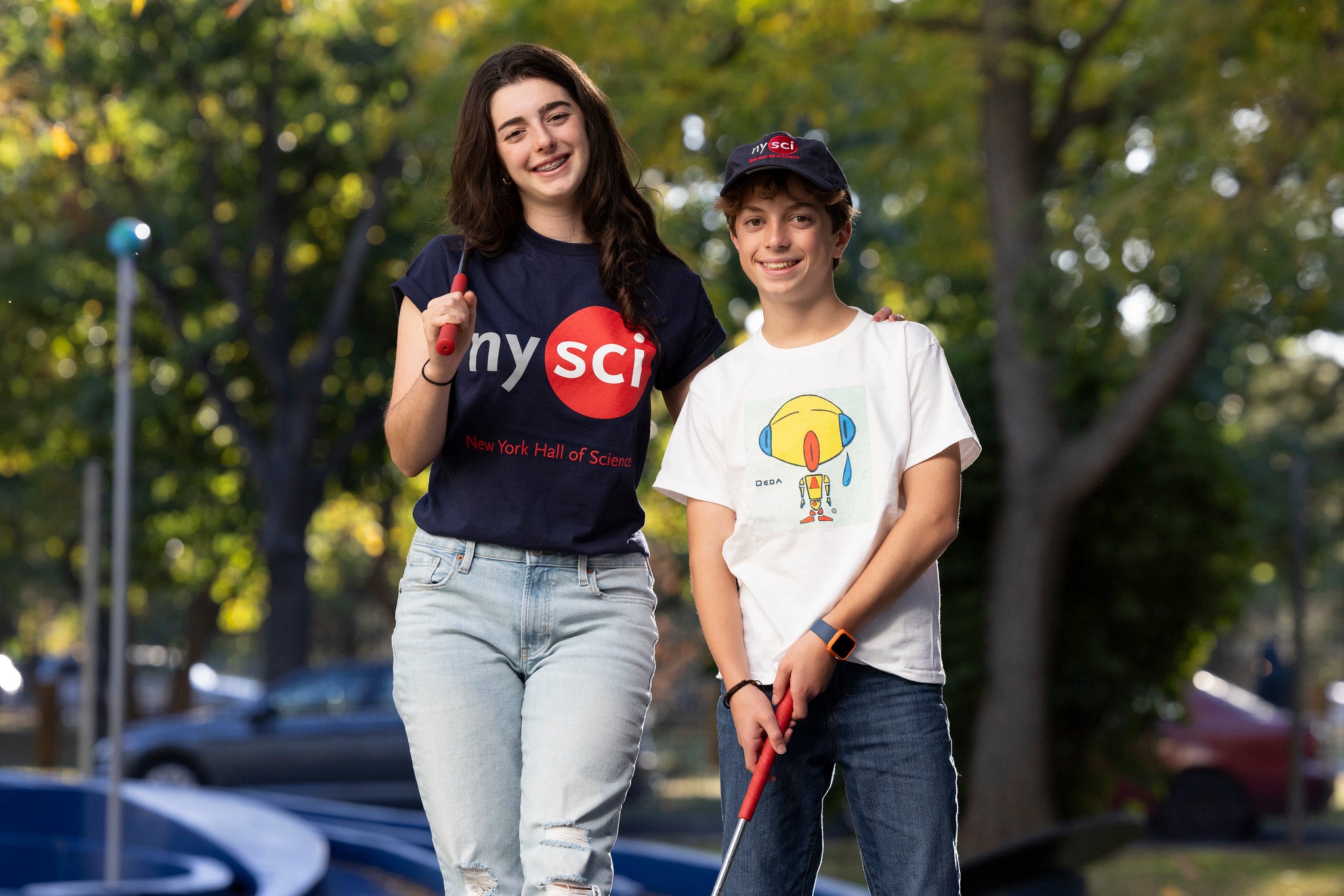 girl and boy playing golf wearing nysci t-shirt and cap