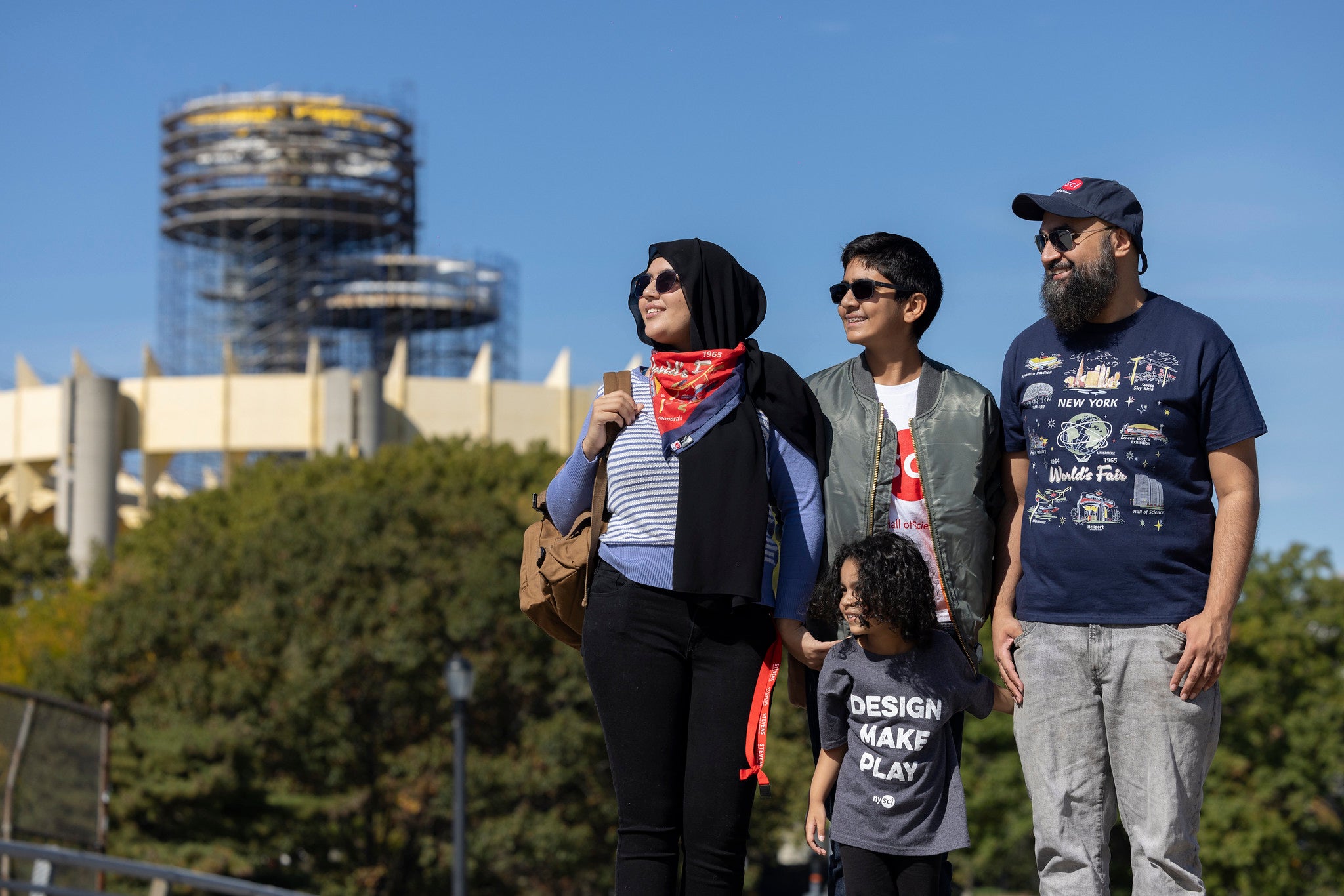 Four people in Corona park wearing different NYSCI branded shirts