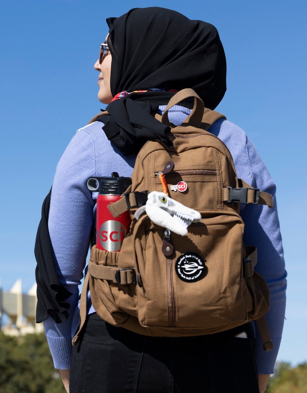 brown canvas backpack on the back of a woman with a water bottle in a side pocket
