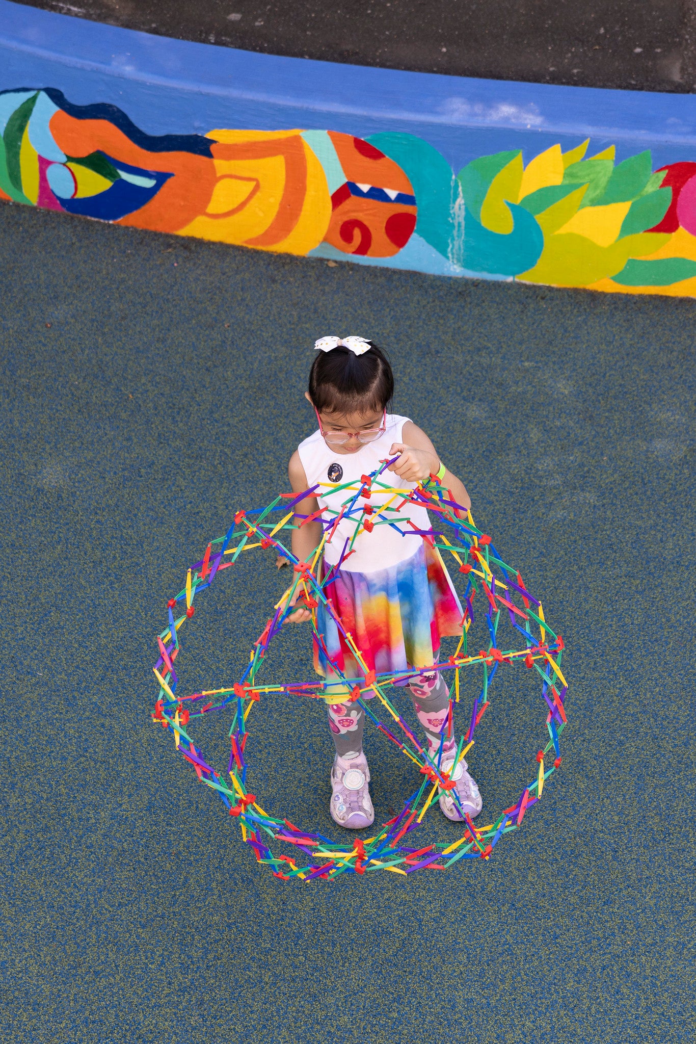 girl playing with colorful expanding sphere outside in playground
