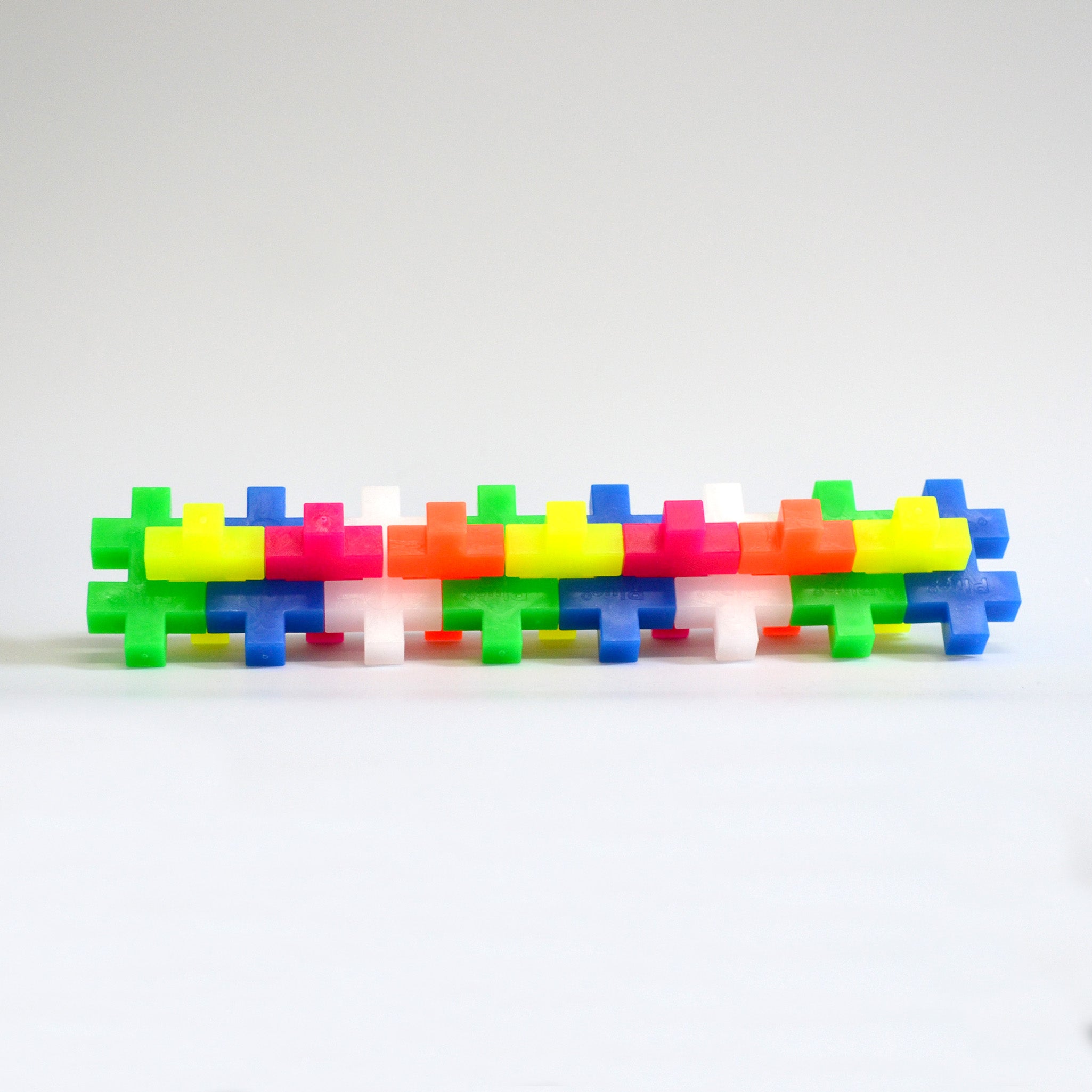 Collectoin of neon colored block puzzle pieces on white background constructed together in a line