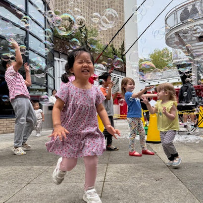Children playing on a sidewalk with a Ferris wheel in the background