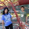 Adult woman wearing blue Queens graphic Tshirt with transit map standing outside