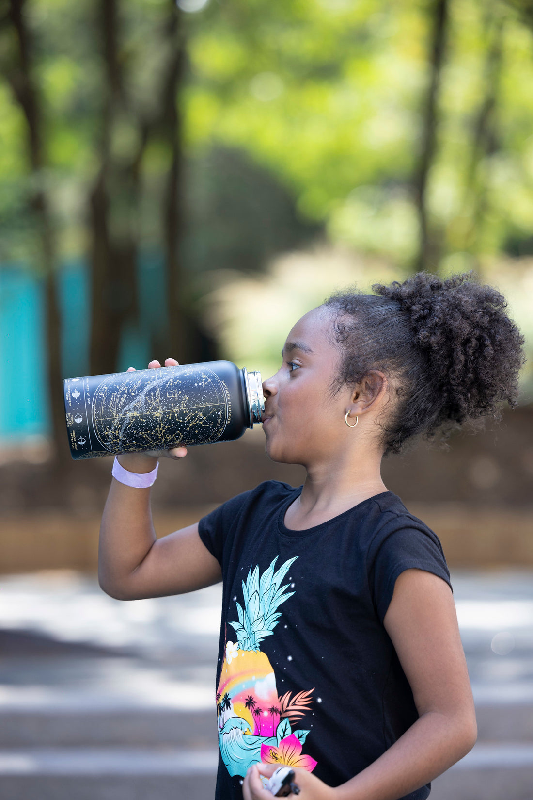 Girl drinking from a black constellation water bottle