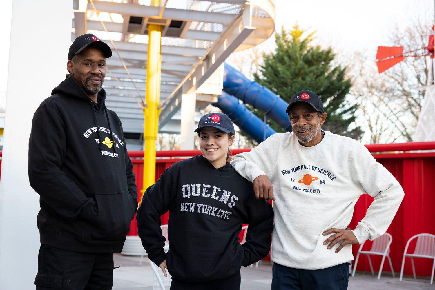 Two men and one woman wearing NYSCI branded sweatshirts and caps