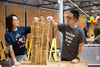A couple playing together as they stack wooden bricks. The man has a grey t-shirt which says DESIGN MAKE PLAY while the woman has a Navy t-shirt which says I Like Science A'Lotl.