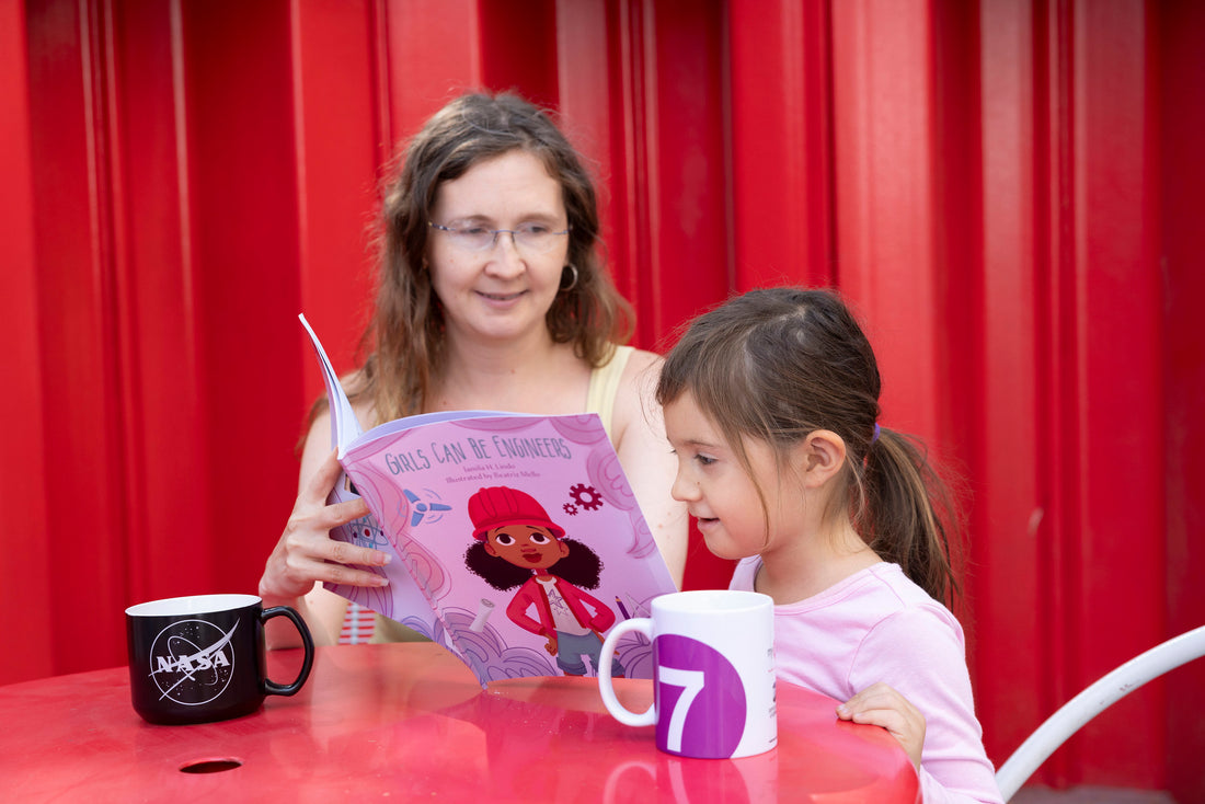 Woman reading to a girl at a red table with NASA and 7 Train branded mugs on the table