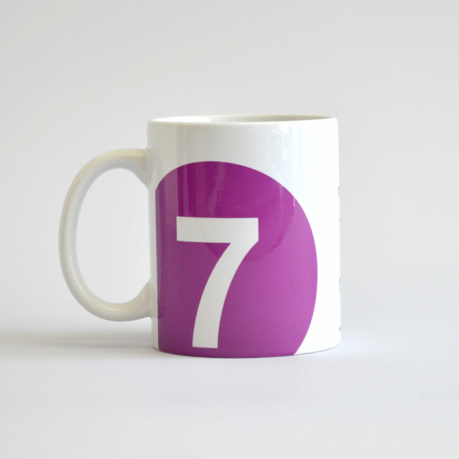 White mug with logo of 7 train in a purple circle