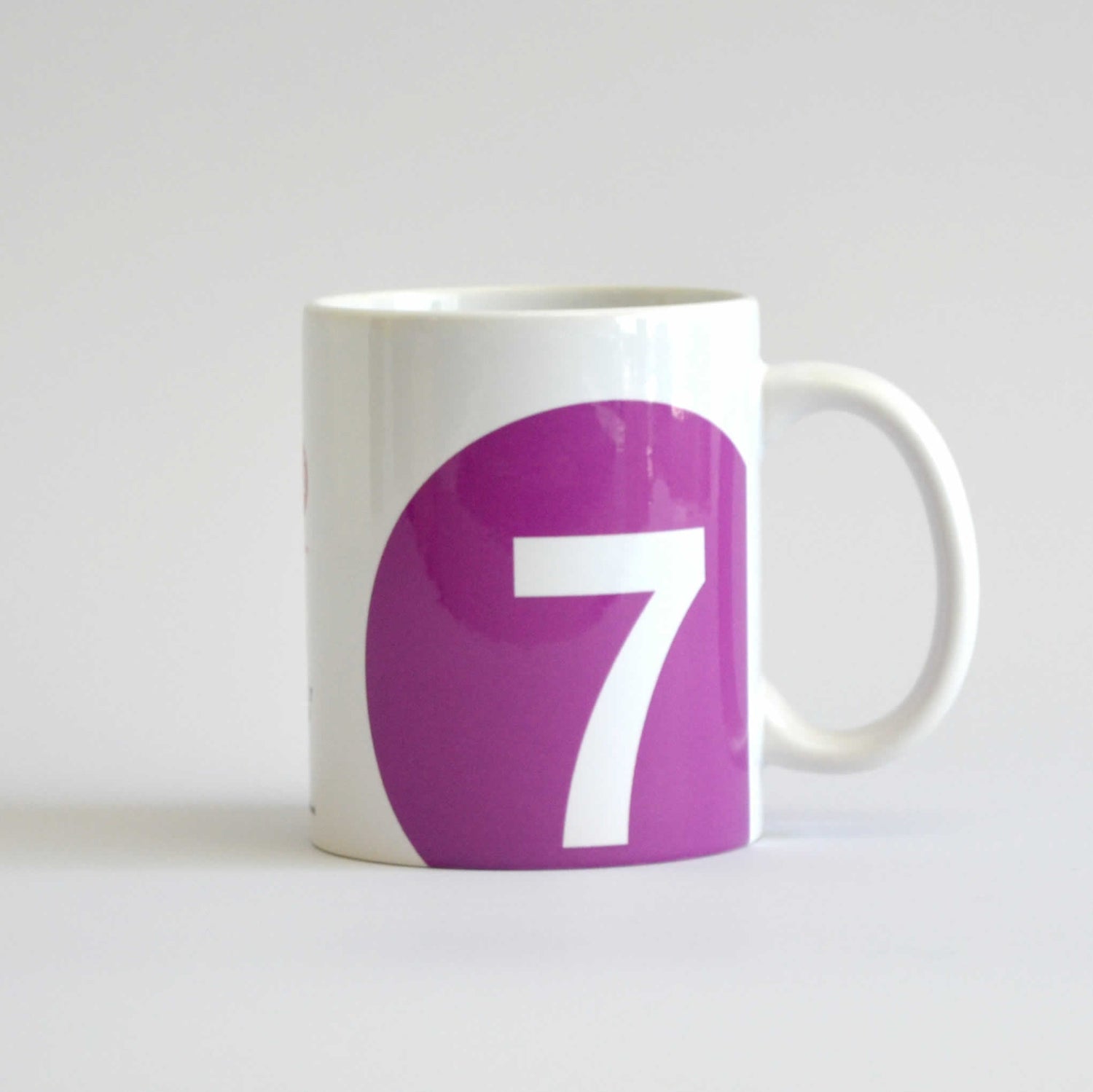 White mug with logo of 7 train in a purple circle