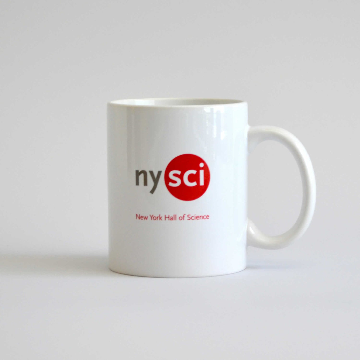 White mug with logo of nysci and the words New York Hall of Science