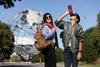 two people with Corona park globe behind them - one has a brown backpack, and the other drinking from a NYSCI water bottle
