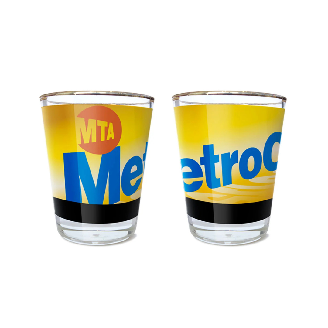 Gold rimmed shot glass with the MetroCard Logo on a white background