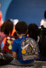 a child with a blue and clear space backpack which has various space ships and shuttles