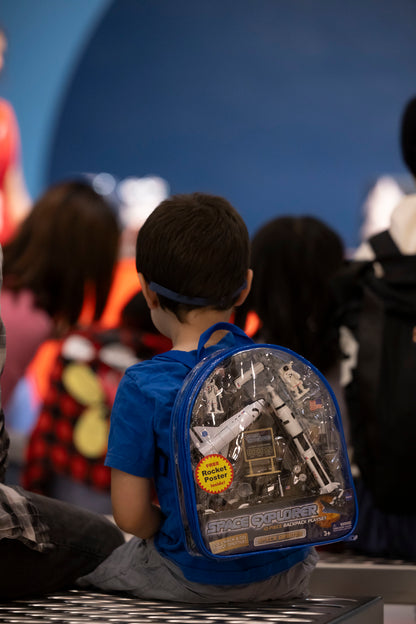 a child with a blue and clear space backpack which has various space ships and shuttles