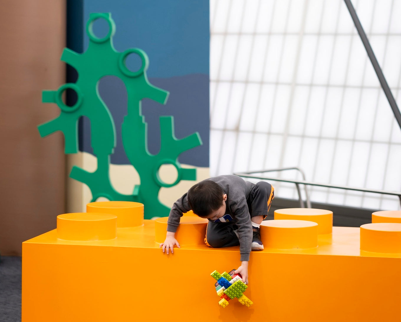 Child playing on a large orange lego piece