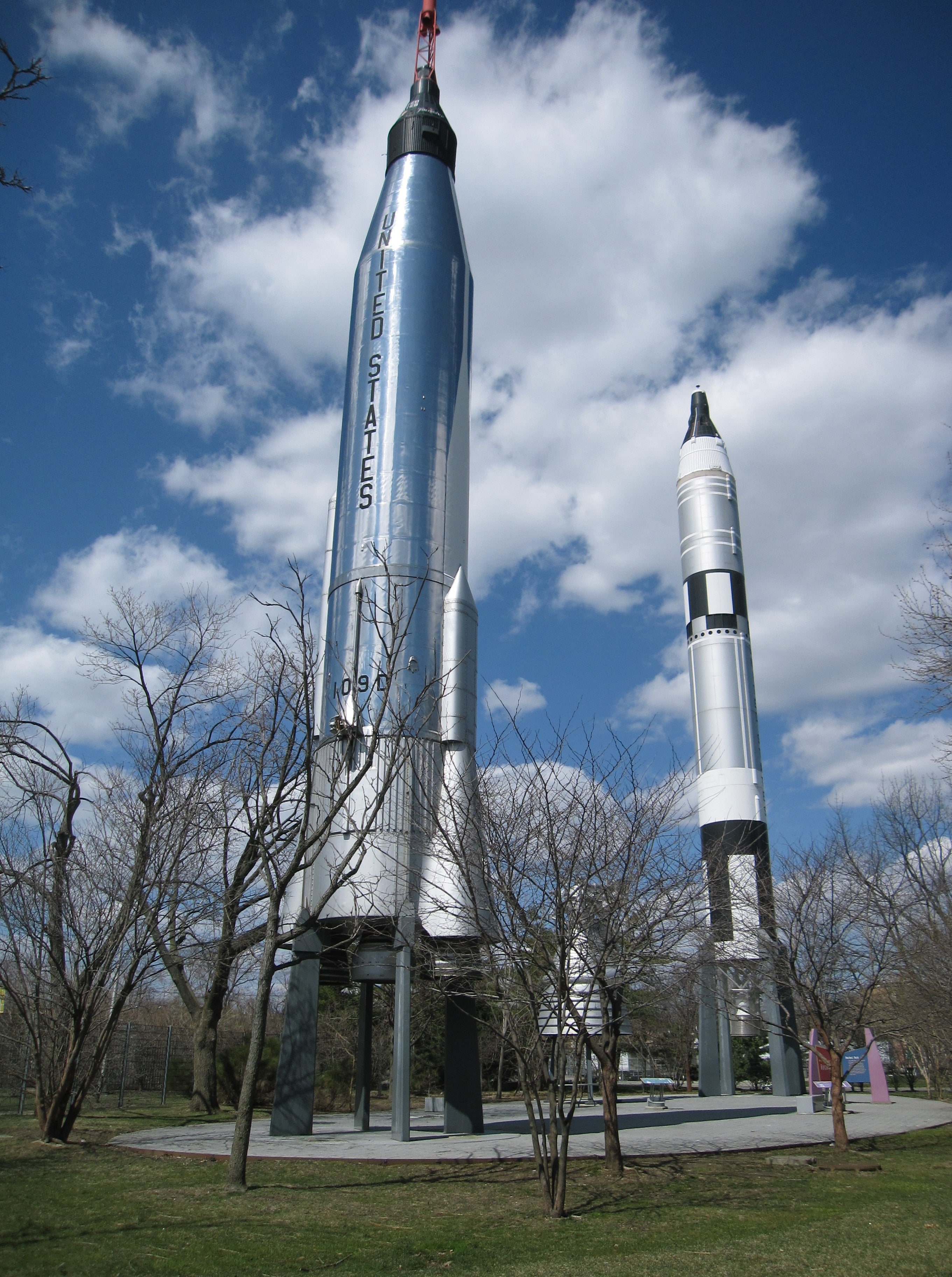 Three silver NASA rockets standing in a garden outside the Hall of Science Museum