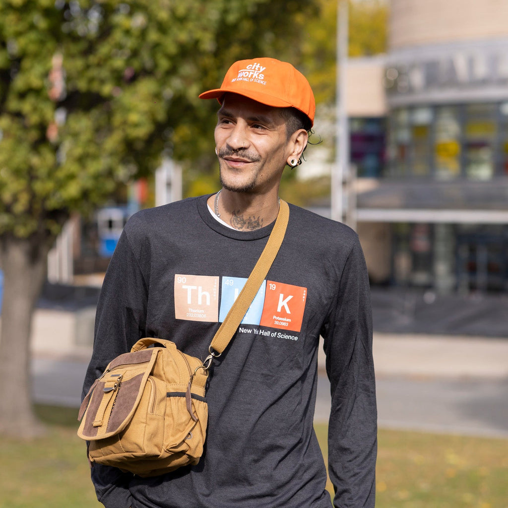 Man wearing orange city works baseball cap, brown sling bag and black think Long sleeve